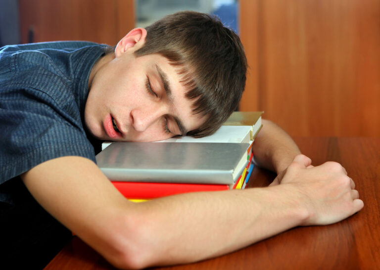 Sleepy teenager asleep on books