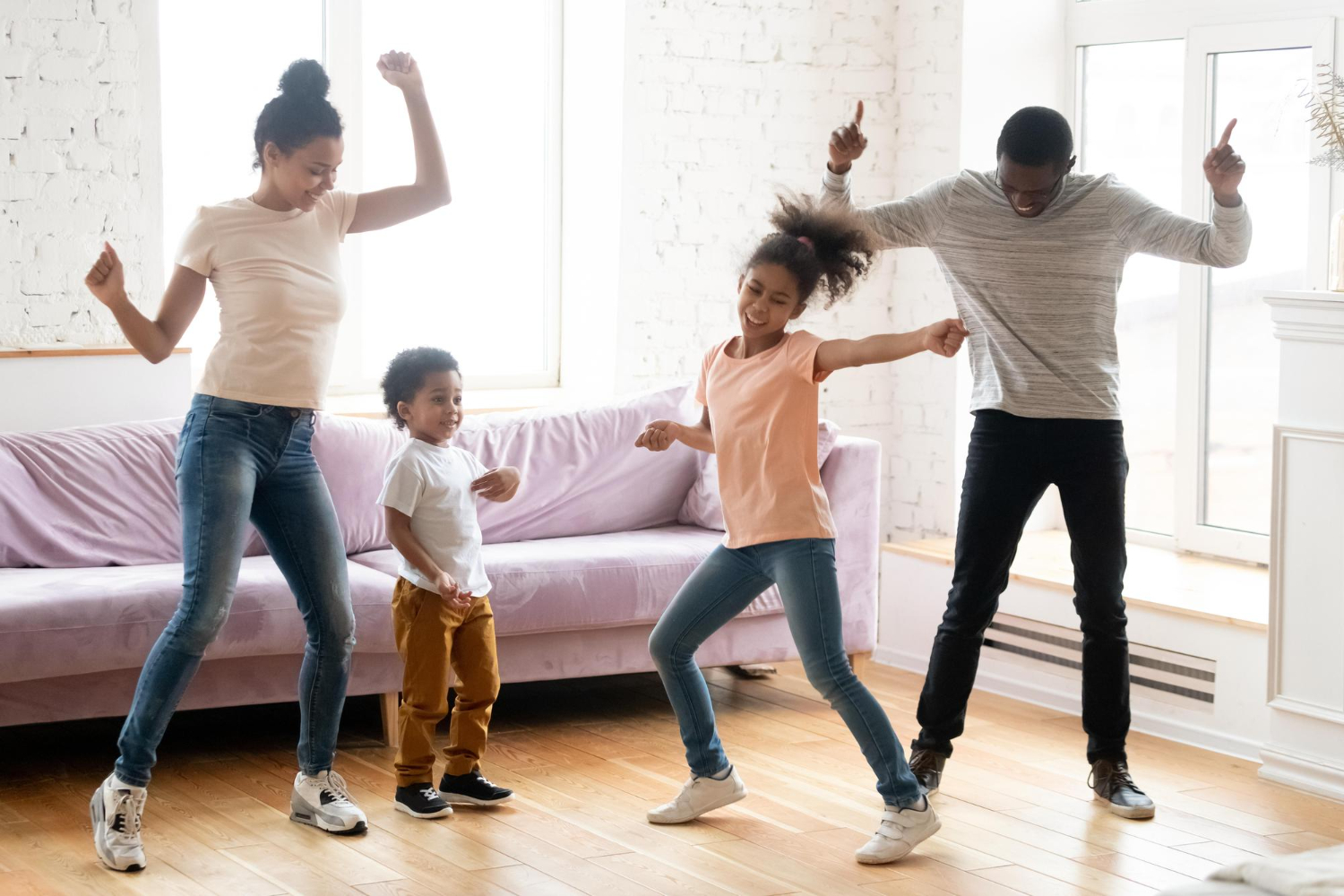 A family of four dances in their living room, showing how to incorporate exercise into everyday activities with kids.