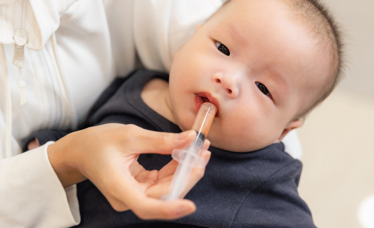 Parent using an oral syringe to give liquid medication to an infant, illustrating safe and convenient medication administration for young children.