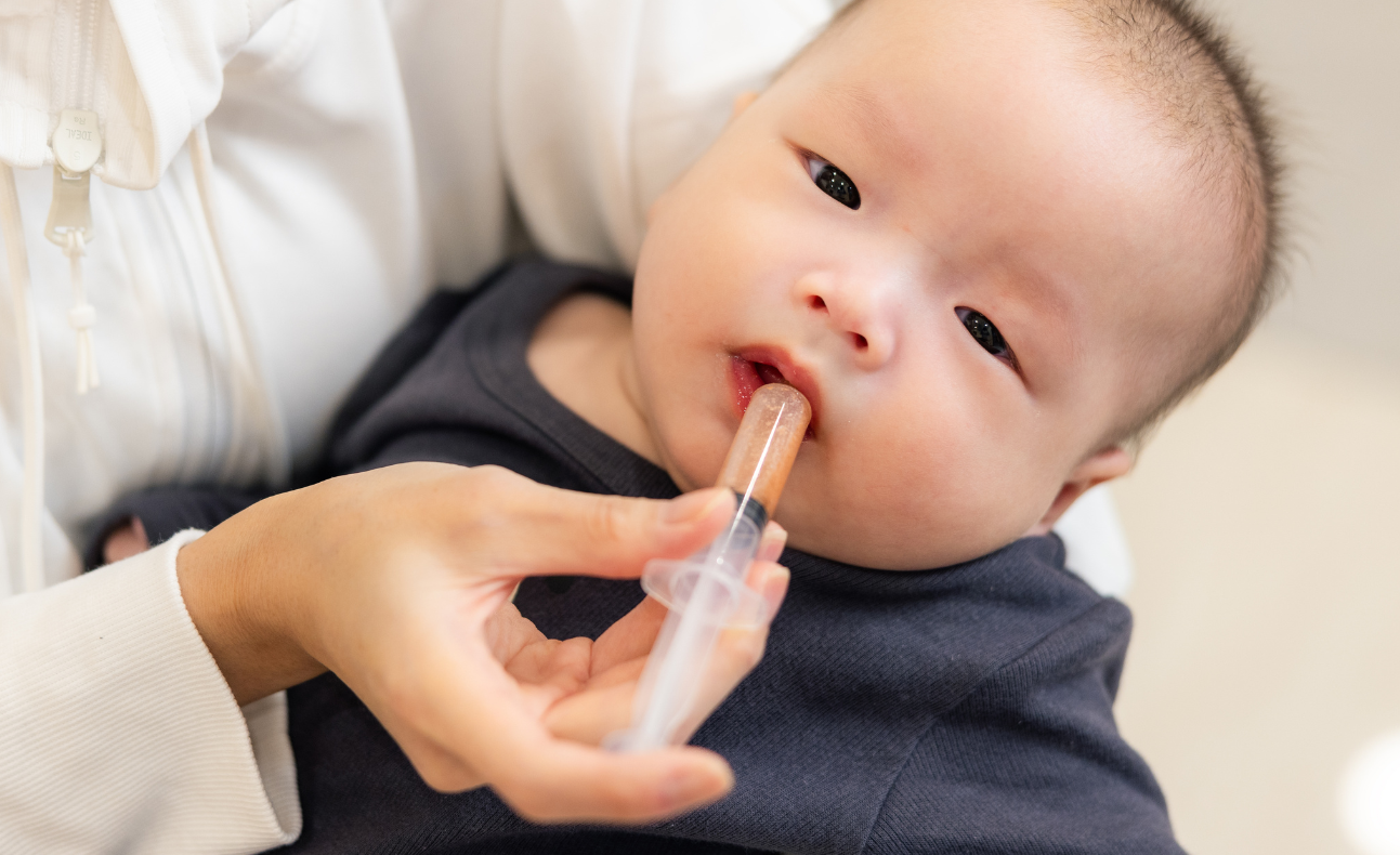Parent using an oral syringe to give liquid medication to an infant, illustrating safe and convenient medication administration for young children.