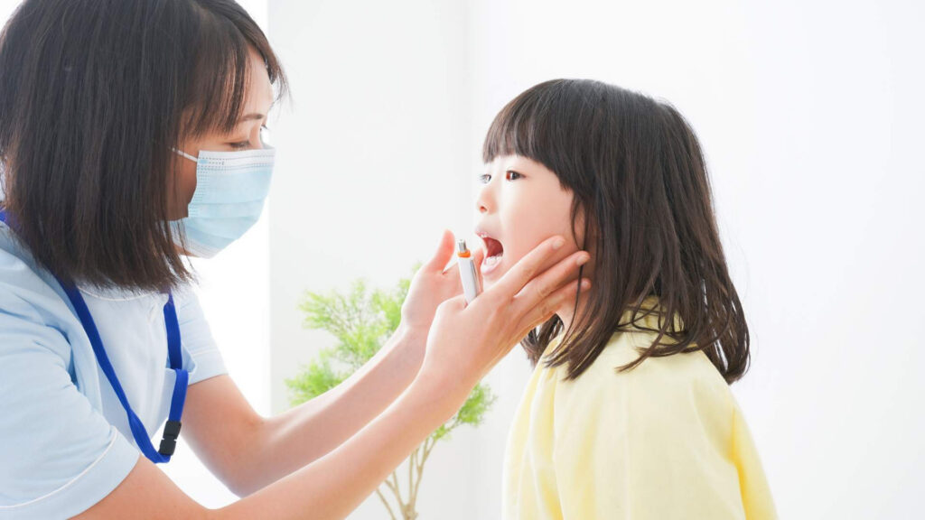 Pediatric provider examining a young girl’s throat during a strep throat evaluation, illustrating how pediatricians diagnose sore throat symptoms and infections in children.